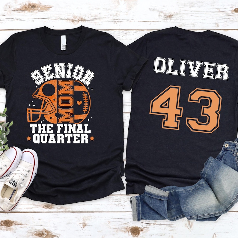 May include: A black t-shirt featuring a front graphic of a football helmet and ball with the text SENIOR MOM THE FINAL QUARTER in orange and white. The back of the shirt displays the name OLIVER and the number 43 in large orange and white text.