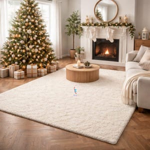May include: A cream-coloured rectangular rug dominates a living room, with a decorated Christmas tree in the background. A fireplace with a lit fire, a round wooden coffee table, and a sofa create a warm, festive atmosphere. The room is decorated for Christmas.