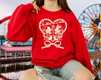 May include: Red sweatshirt with a white graphic of Mickey and Minnie Mouse sitting at a table with the text "So this is Love."