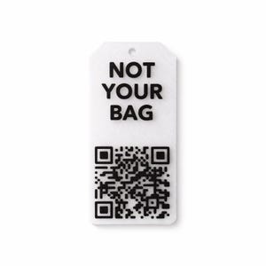 Könnte beinhalten: Ein weißes rechteckiges Etikett mit abgerundeten Ecken und einem Loch oben. Der Text "NOT YOUR BAG" in Schwarz befindet sich über einem schwarzen QR-Code.