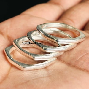 Könnte beinhalten: Vier silberne Ringe mit quadratischem Design, die übereinander gestapelt sind. Die Ringe sind glänzend und reflektieren das Licht. Die Ringe befinden sich auf einer Hand. Der Text "RubyJewellery925" ist sichtbar.