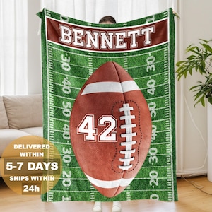 May include: A rectangular fleece blanket featuring a green football field pattern with white yard lines and numbers. A large brown football with white laces and the number 42 is centered. The name BENNETT is printed in white on a dark red banner.