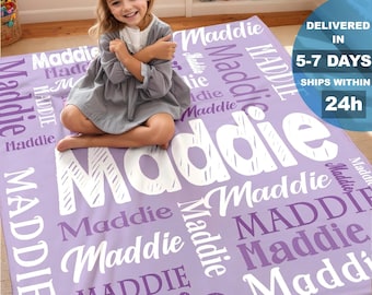 May include: A lavender blanket with the name "Maddie" printed in white in various fonts and sizes. The blanket is rectangular and appears to be soft. The text "Delivered in 5-7 days, ships within 24h" is also visible.
