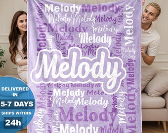 May include: A light purple fleece blanket featuring the name Melody printed repeatedly in various white and dark purple fonts, with one large, prominent Melody in white script centered across the middle of the fabric surface.