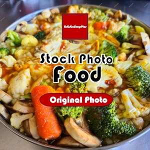 Op de afbeelding: Een roestvrijstalen pan gevuld met een roerbakgerecht van broccoliroosjes, bloemkool, gesneden bruine champignons en een hele oranje wortel. De afbeelding bevat de tekst ArtisticShopPlus, Stock Photo Food en Original Photo.