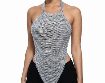 May include: A silver-toned chainmail halter top featuring a fine interlocking metal ring construction. The garment has a high neckline with straps that wrap around the neck and a pointed, elongated hemline that extends downwards in a V-shape.