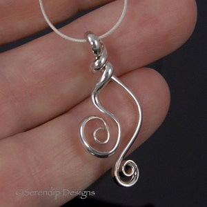 May include: A silver pendant with a swirling, abstract design. The pendant features a spiral at the bottom and a twisted section at the top, suspended on a thin, white cord. The design is minimalist and elegant.