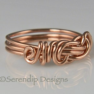 Puede incluir: Un anillo artesanal de alambre de cobre con un dise&ntilde;o &uacute;nico tejido. El anillo presenta m&uacute;ltiples bucles y espirales, creando una apariencia intrincada y art&iacute;stica. El anillo es de color cobre c&aacute;lido y se muestra sobre un fondo claro.