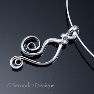May include: A silver-colored pendant necklace with a swirling, abstract design. The pendant features a curved shape with a spiral at one end and is suspended from a thin, silver-colored chain. The background is a dark, reflective surface.