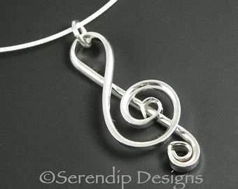May include: A silver treble clef pendant necklace. The pendant is made of wire and is shaped like a treble clef. The necklace is on a silver chain.