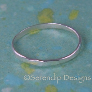 May include: A simple silver band ring with a hammered texture.