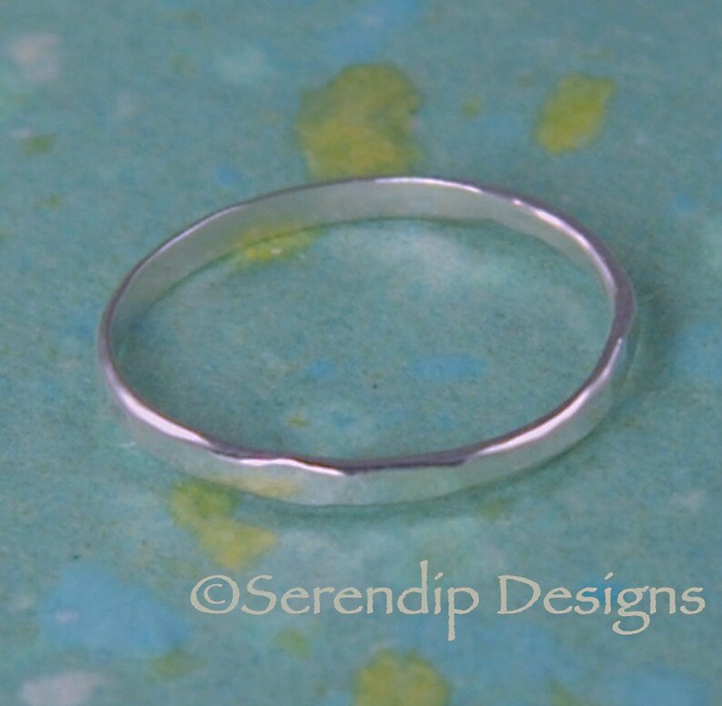May include: A simple silver band ring with a hammered texture.
