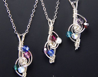 May include: Three silver necklaces with a spiral pendant design. Each pendant features a different combination of blue, purple, and green crystals and a white pearl.