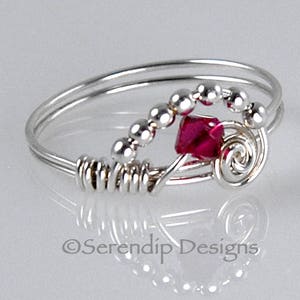 May include: A silver ring with a pink crystal and silver beads. The ring is made of wire and has a spiral design.
