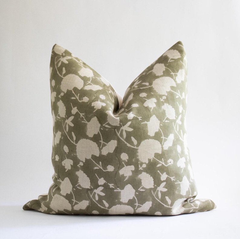 Puede incluir: Una funda de coj&iacute;n con estampado floral verde y blanco. La funda de coj&iacute;n est&aacute; hecha de una tela de lino suave y presenta un dise&ntilde;o floral sutil y descolorido.