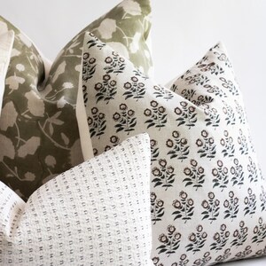 Puede incluir: Tres almohadas decorativas con diferentes patrones. La primera almohada es de color verde claro con un patr&oacute;n floral blanco. La segunda almohada es blanca con un patr&oacute;n floral negro y marr&oacute;n. La tercera almohada es blanca con un patr&oacute;n de peque&ntilde;os puntos negros.