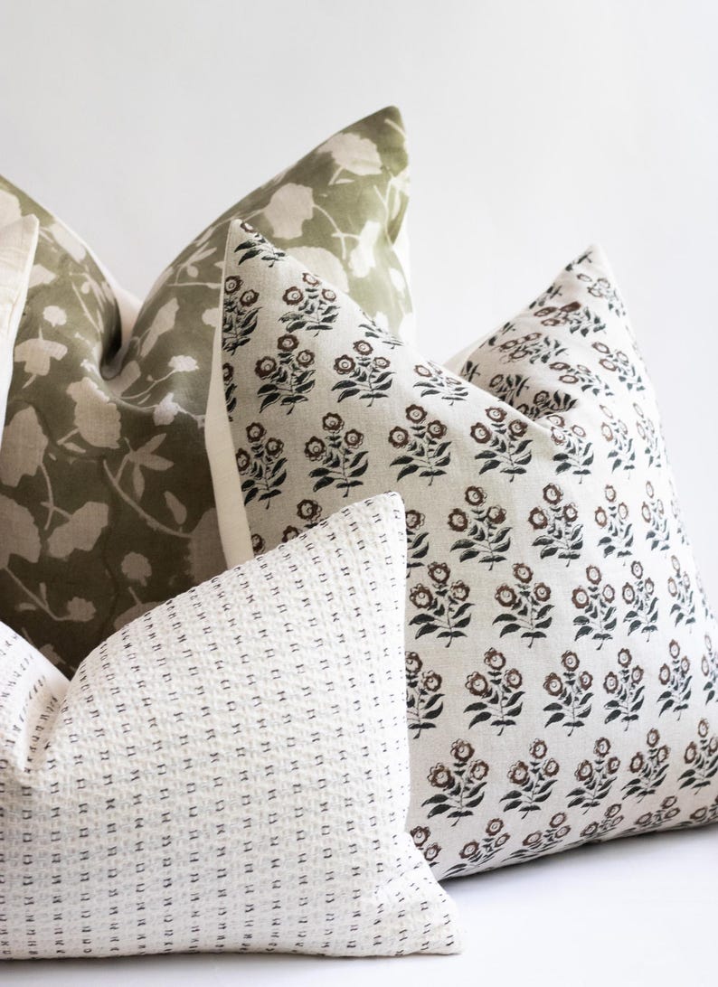 Puede incluir: Tres almohadas decorativas con diferentes patrones. La primera almohada es de color verde claro con un patr&oacute;n floral blanco. La segunda almohada es blanca con un patr&oacute;n floral negro y marr&oacute;n. La tercera almohada es blanca con un patr&oacute;n de peque&ntilde;os puntos negros.