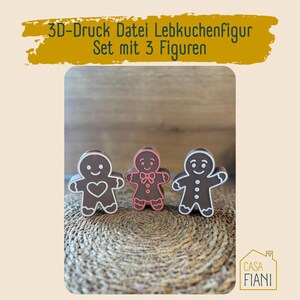 Könnte beinhalten: Drei Lebkuchenmann-Figuren mit weißen Umrissen und Details. Einer hat ein Herz, einer eine Schleife und der dritte Knöpfe. Der Text "3D-Druck Datei Lebkuchenfigur Set mit 3 Figuren" steht oben.