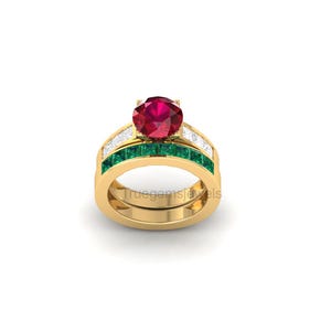 May include: A gold ring with a large, round, red gemstone at the center. The ring features a band of small green gemstones and a band of small white gemstones. The text "truegemsjewels" is visible on the ring.