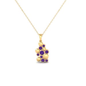 May include: A gold necklace with a pendant. The pendant has a cluster of gold spheres and purple gemstones. The necklace hangs from a delicate chain. The gemstones are round and set within the gold spheres.