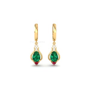 May include: A pair of gold earrings with a teardrop design. Each earring features a large, pear-shaped green gemstone, a small red gemstone, and three small white gemstones. The earrings are suspended from a gold hoop.