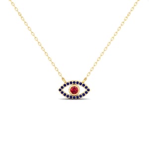 May include: A gold-colored necklace featuring an eye-shaped pendant. The pendant has a red center, surrounded by a ring of blue stones. The necklace chain is delicate and gold-colored, creating a simple yet elegant design.
