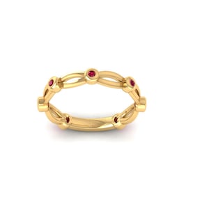 May include: A gold ring with a repeating design. The ring features small, round, red gemstones set at intervals along the band. The ring has a polished, reflective surface.