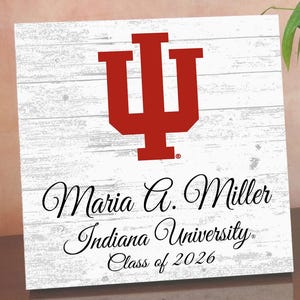 May include: Square wooden sign with a white, distressed wood background. A large red Indiana University logo is at the top. Below, elegant script reads "Maria G. Miller, Indiana University, Class of 2026."