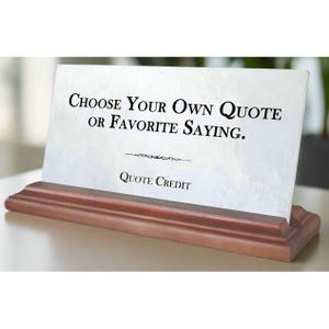 May include: A white plaque with a wooden base. The plaque has the text "Choose Your Own Quote or Favorite Saying." and "Quote Credit" printed on it.