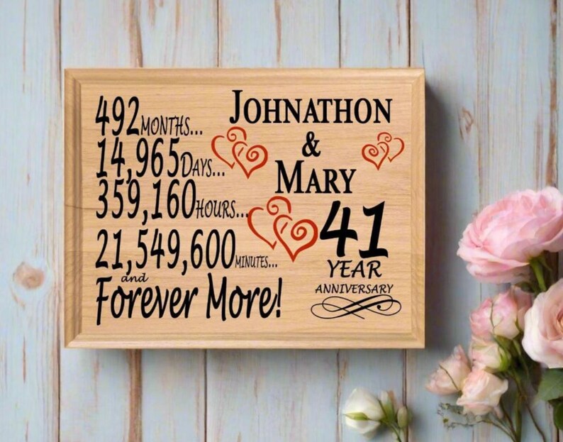 May include: A wooden sign with the text "Johnathon & Mary 41 Year Anniversary" and a list of time periods in months, days, hours, and minutes. The sign is decorated with red hearts.