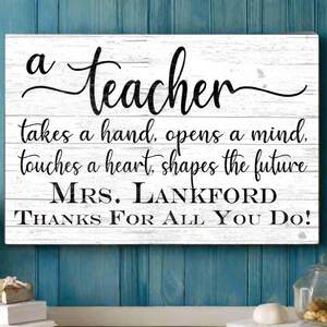 May include: White wooden sign with black text that reads "a teacher takes a hand, opens a mind, touches a heart, shapes the future MRS. LANKFORD THANKS FOR ALL YOU DO!"