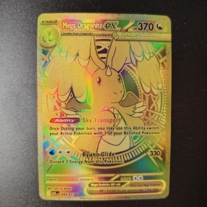 Op de afbeelding: Een goudkleurige Mega Dragonite EX ruilkaart met een holografische afwerking. De kaart bevat een illustratie van een draakachtig wezen, de tekst Mega Dragonite EX, 370 HP, de Sky Transport-vaardigheid en de Ryuno-Glide-aanval met 330 schade.