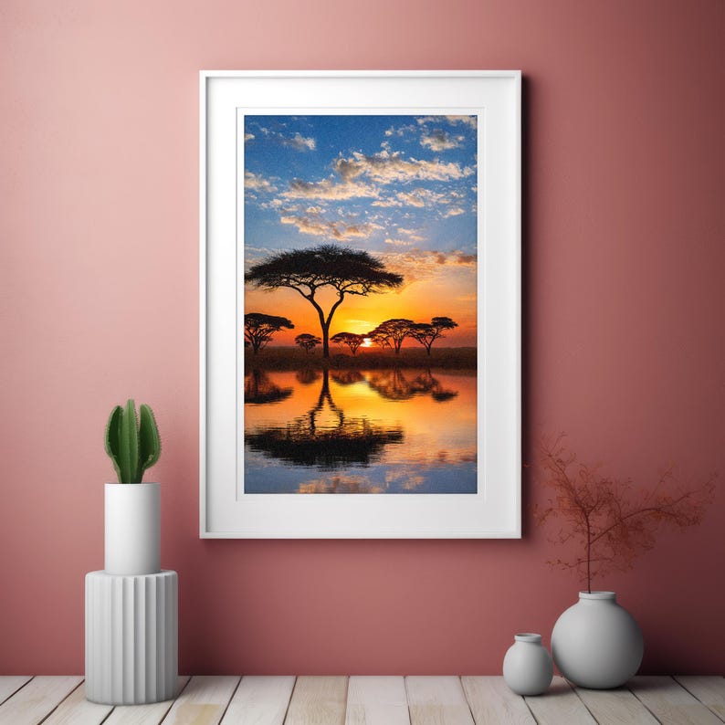 May include: Framed landscape art print featuring a sunset over a body of water with silhouetted trees. The sky transitions from blue to orange, reflecting in the water. The print is in a white frame.