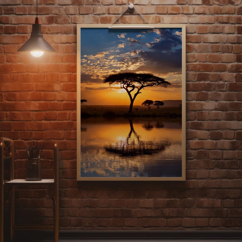 May include: A framed print of an African savanna landscape at sunset. The image features a large tree silhouetted against a vibrant orange and yellow sky, reflected in the calm water below. The scene evokes a sense of peace and tranquility.