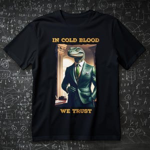 Może przedstawiać: Czarna koszulka z dinozaurem w zielonym garniturze i krawacie. Złoty tekst "IN COLD BLOOD WE TRUST" jest wydrukowany nad i pod ilustracją. Tło to tablica.