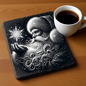 Może przedstawiać: Czarno-biały podkładka z łupków z szczegółową ilustracją Świętego Mikołaja trzymającego płatek śniegu. Biały kubek wypełniony ciemnym płynem znajduje się po prawej stronie podkładki na drewnianej powierzchni. Podkładka ma teksturowaną powierzchnię.
