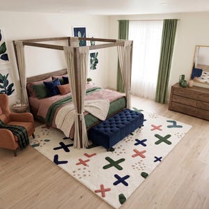 Puede incluir: Un dormitorio con una cama con dosel de madera y cortinas beige, un banco capitoné azul marino y una alfombra color crema con un patrón multicolor de cruces y puntos. A la izquierda hay un sillón naranja con una manta de cuadros verdes.