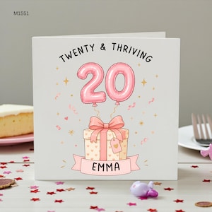 Op de afbeelding: Een vierkante wenskaart met een witte achtergrond en de tekst TWENTY & THRIVING bovenaan. Daaronder twee roze balloncijfers die een 20 vormen, vastgebonden aan een cadeau met een roze strik en een label met EMMA op een roze banner onderaan.
