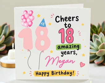 May include: A white birthday card with the number 18 in pink, decorated with balloons and stars. The card reads "Cheers to 18 amazing years, Megan, Happy Birthday!" in a mix of fonts and colors.