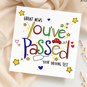 May include: A white greeting card with the words "Great News You've Passed Your Driving Test" in colorful, whimsical lettering. The card is decorated with stars, hearts, and a small red car illustration.