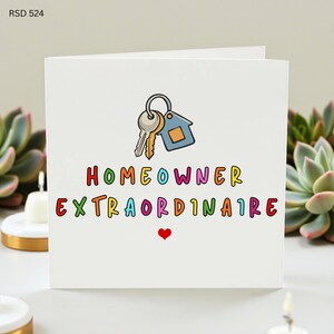 Puede incluir: Tarjeta de felicitación blanca con las palabras "HOMEOWNER EXTRAORDINAIRE" en letras coloridas. La tarjeta presenta un llavero con llaves y una etiqueta con forma de casa, y un corazón rojo.