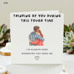 Może przedstawiać: Biała kartka z napisem "THINKING OF YOU DURING THIS TOUGH TIME". Na środku znajduje się ilustracja dwóch osób obejmujących się. Na kartce widnieje również napis "I'M ALWAYS HERE WHENEVER YOU NEED ME" ze symbolem serca poniżej.