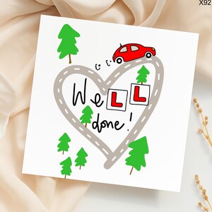 May include: A white greeting card with a heart-shaped road design, a red car, and green trees. The text "Well done!" is written in black script. Two squares with the letter "L" are also present.