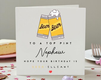 May include: A white square greeting card featuring a graphic of two yellow beer glasses clinking together with white foam. The text reads: TO A TOP PINT Nephew HOPE YOUR BIRTHDAY IS BEER-ILLIANT, with a small red heart icon at the bottom center.