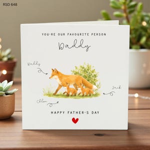 Könnte beinhalten: Eine Vatertagskarte mit einer Aquarellillustration einer Fuchsfamilie. Die Karte trägt die Aufschrift "You're our favourite person Daddy" mit den Namen "Dally", "Chloe" und "Jack". Die Worte "Happy Father's Day" stehen ebenfalls auf der Karte.