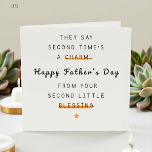 Può includere: Un biglietto bianco per la festa del papà con la scritta "THEY SAY SECOND TIME'S A CHARM... Happy Father's Day FROM YOUR SECOND LITTLE BLESSING". Il biglietto ha una piccola stella arancione in basso.
