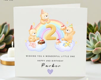 May include: A birthday card with a watercolor illustration. The card features three teddy bears, a rainbow, and the number 2. Text on the card reads "Wishing you a wonderful little one", "Happy 2nd Birthday", and "Parker". A purple heart is at the bottom.