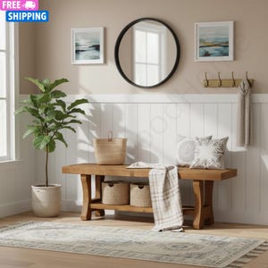 May include: A wooden entryway bench with a lower shelf, featuring two woven baskets, a draped plaid throw blanket, and two decorative pillows. The bench is positioned near a potted fiddle leaf fig plant, a round black mirror, and a wall-mounted coat rack.