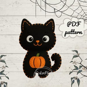 Könnte beinhalten: Schwarze Filzkatze mit orangefarbenem Kürbis und gestickten Details. Die Katze hat große weiße Augen und eine orangefarbene Nase und Mund. Der Text "PDF pattern" ist enthalten. Halloween-Thema.