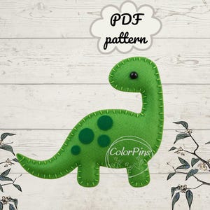 May include: A green felt dinosaur with a long neck and tail, featuring dark green spots and stitched details. The image includes the text "PDF pattern" in a cloud-shaped graphic, and the ColorPins logo.